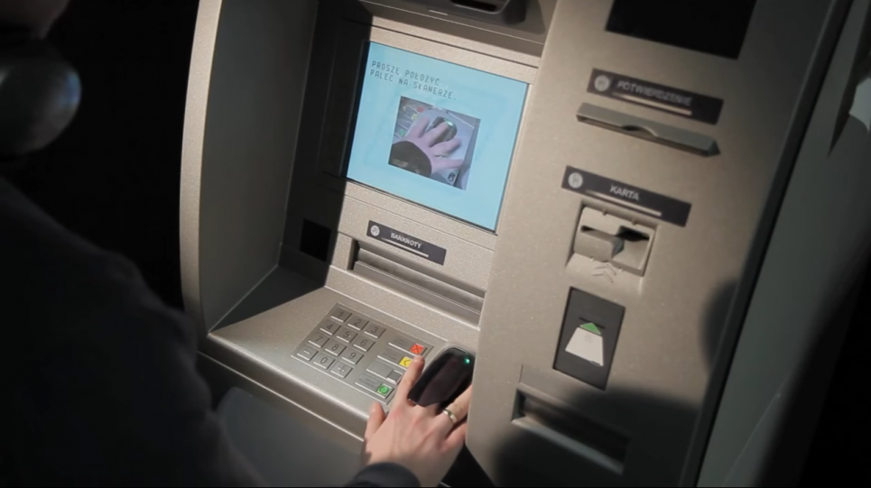 Person scanning finger while using an ATM